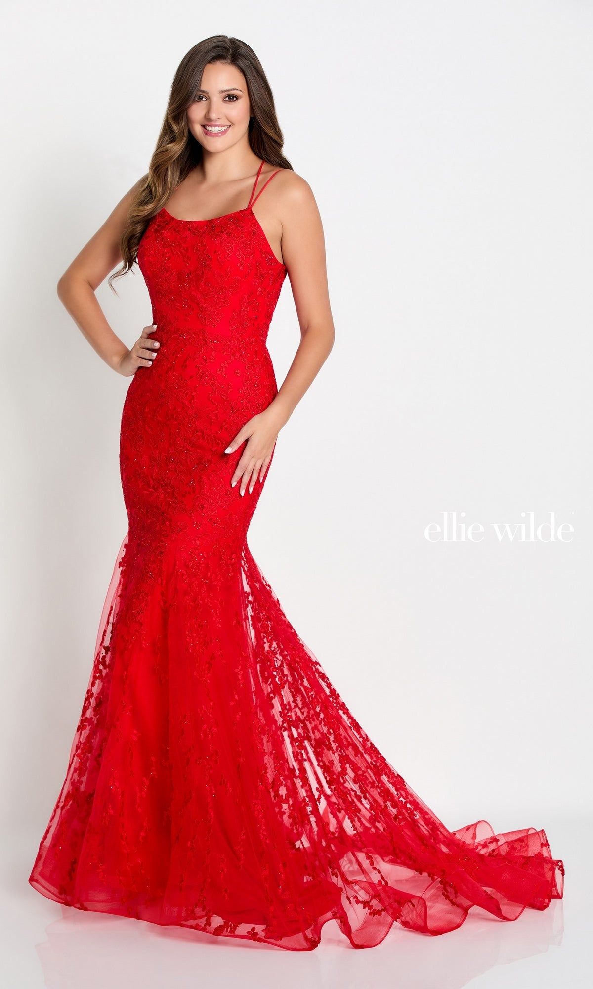 A woman poses in a fitted, floor-length bright red Long Lace Mermaid Prom Dress with a strappy back and lace embellishments, standing against a plain white background.